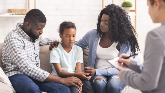 Photograph of a family, Mum, Dad and a young girl talking to someone off camera 