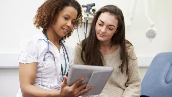 A doctor shows a young woman information in a medical consultation.