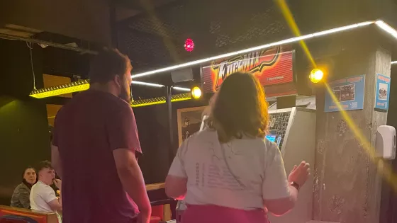 Two young people compete on a dancing machine in an arcade.