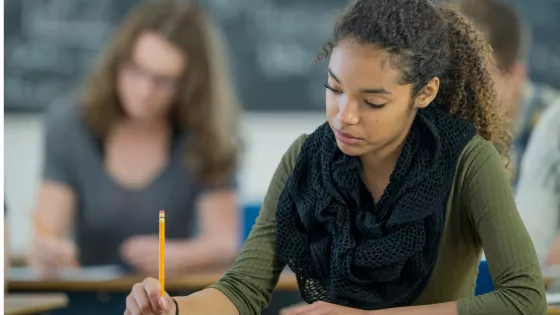 A young woman focuses as she fills in a paper in an examination.