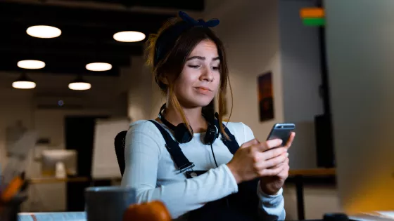 A young woman looks at her phone with a concerned expression.
