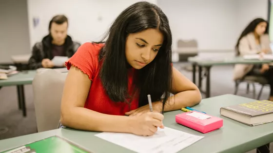 Young girl writing on an exam paper in an exam hall