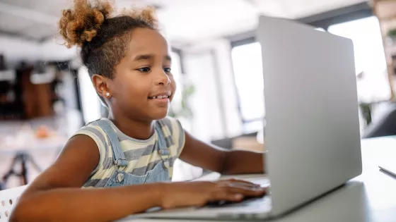 Young girl on a laptop half smiling