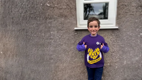 Young boy smiles with thumbs up wearing a 26 miles for 26 days for purple day t-shirt