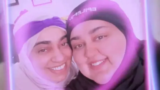 Two women in headscarves smile in a filtered selfie.