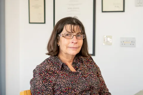 Professor Helen Cross smiles slightly to camera in an office setting.