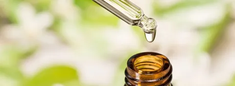 CBD oil drips from a pipette into a medicinal bottle.