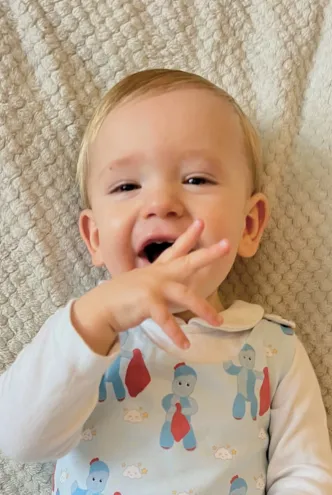 A young boy who lives with epilepsy smiles and gestures from his bed.