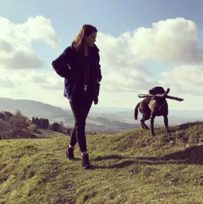 a girl walking her dog on a hill
