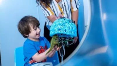 Young boy inspects the OPM MEG helmet