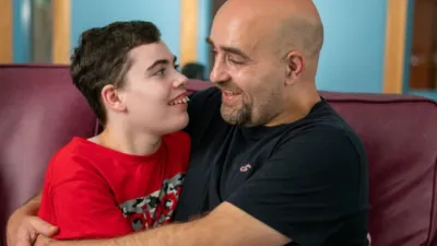 A young boy is seen smiling, being held by his father