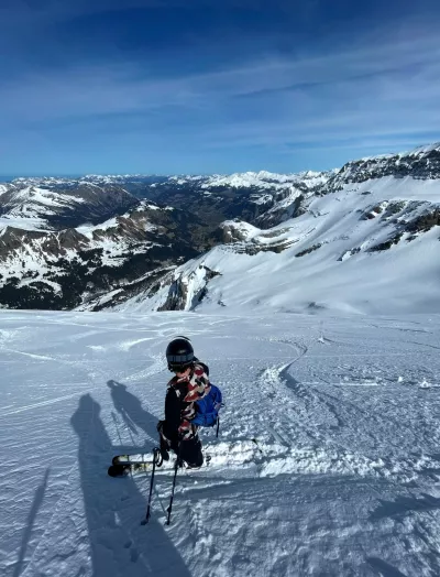 A snowboarder looks down a steep, snowy mountain slope.