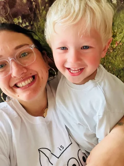 A dark haired mother and her blonde haired son smile in camera.