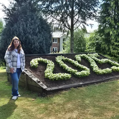 Laura, a young woman, stands by a floral arrangement that reads '2025'.