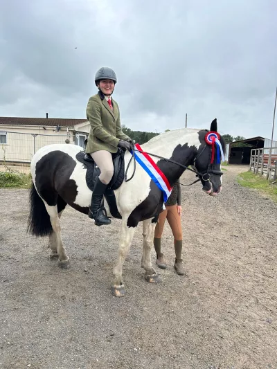 A young woman, Liberty, sits atop a black and white horse.
