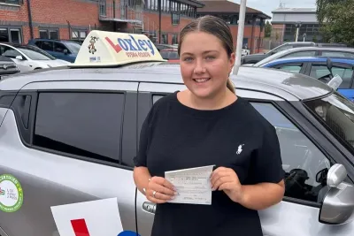 A young woman stands by a learner car, showing that she passed her driver's license.