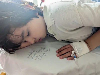 A young boy lies down in a hospital bed.