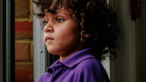 A young boy in a St. Piers School looks out of window thoughtfully.