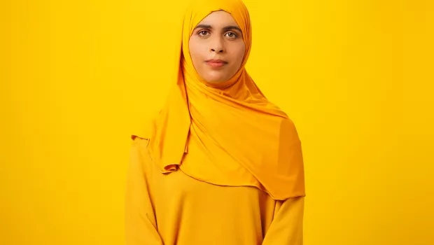 Zunera wearing a yellow head scarf in front of a yellow backdrop