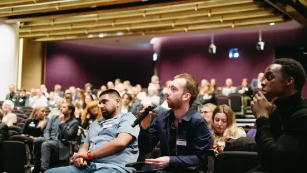 A young man asks a question on the microphone at a Young Epilepsy conference.