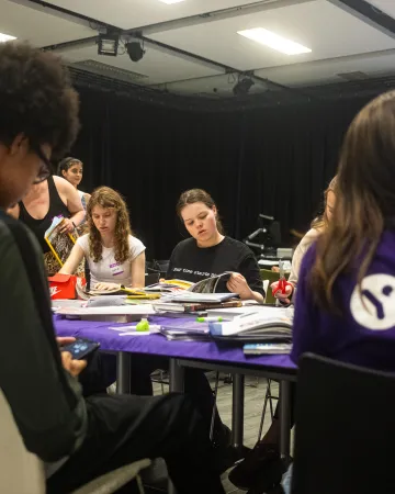 A group of young people make make collages at a table in Young Epilepsy clothing.