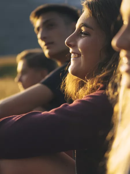 Four teenage friends smile looking into the distance with the sunset lighting their faces