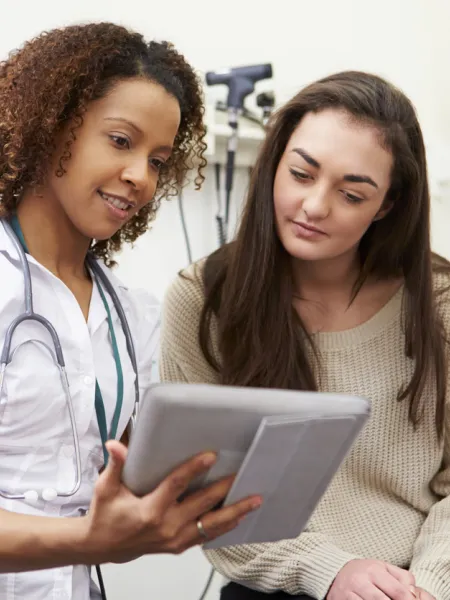 A doctor shows a young woman information in a medical consultation.