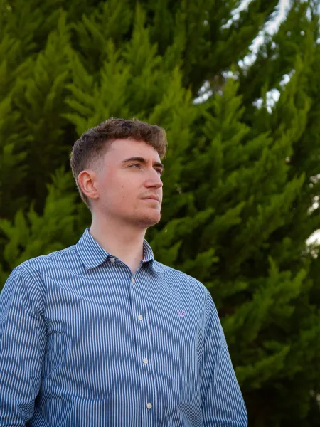 A young man in a blue shirt looks beyond the camera.