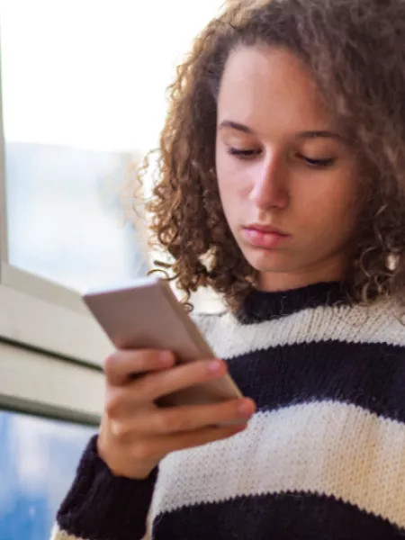 A young person looking at down at her phone concentrating.