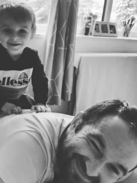 A young boy sitting on his father's back smiling