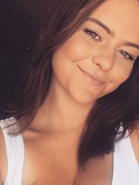 Jasmine, a young woman in white vest, smiles with her head tilted in a selfie.