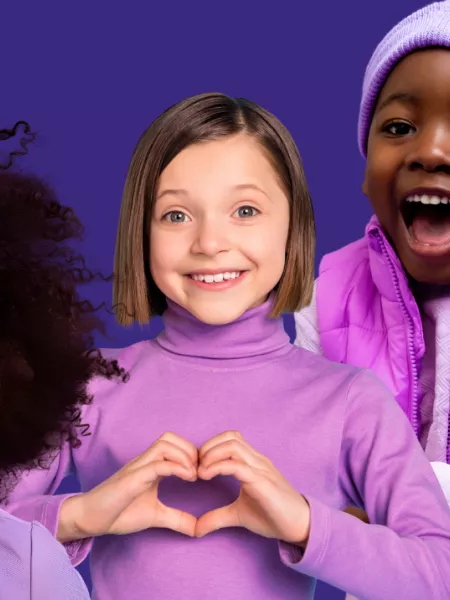Three young children smiling and wearing purple