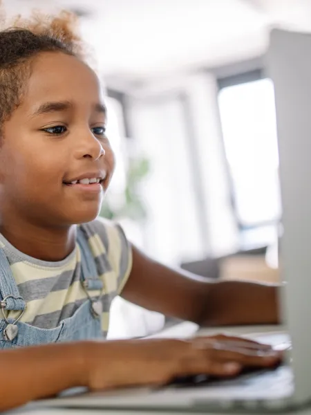 Young girl on a laptop half smiling