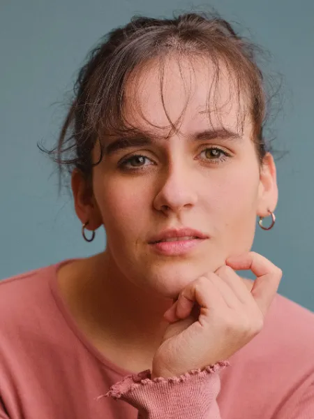 A young woman, Rebecca, looks thoughtfully off-camera.