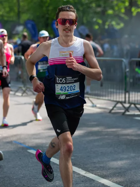 Jack give a thumbs up as he runs along a marathon route.