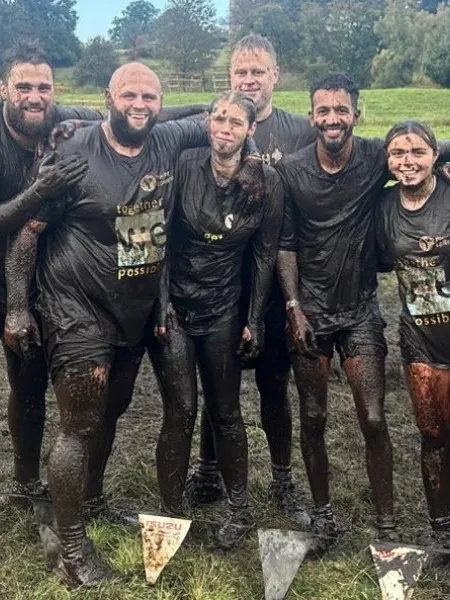 Muddy group of friends smiling at a cemera