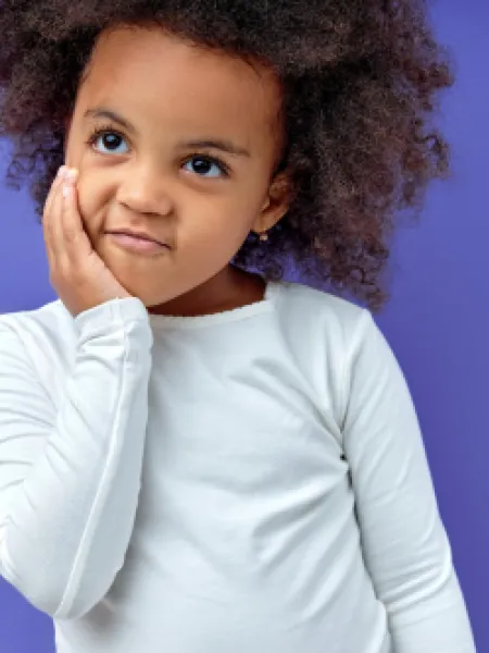 Young girl with hands to face, thinking against a purple backdrop
