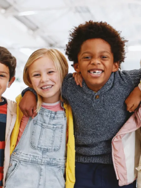 A group of young children smile while holding shoulders on the cover of a Young Epilepsy research report.