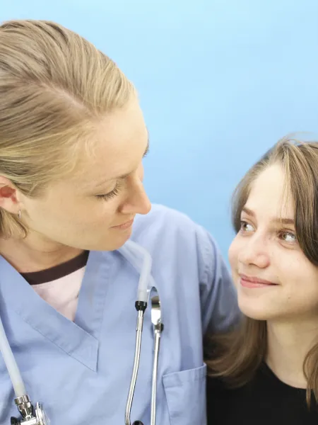 A female medical professional comforts a young girl.